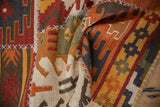 Raised ivory cross-hatch stitches over textured, geometric patchwork kilim panels.
