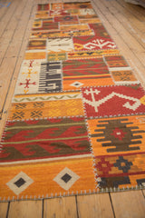 Long view of a patchwork kilim runner with warm geometric patterns and stitched seams.