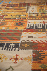 Primitive geometric motifs and distinct white cross-stitch seams on a patchwork kilim rug.