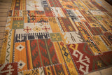 Warm patchwork kilim rug showing geometric panels and raised cross-hatch stitching.