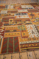 Saffron yellow and brick red kilim patchwork panels with geometric motifs and white cross-stitch seams.