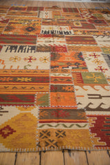 Close-up of geometric patchwork panels in brick red, tangerine, olive, and ivory, with cross-hatch stitches.