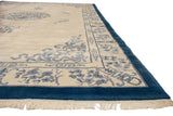 Indigo blue border, ivory floral corner, and visible missing fringe of a vintage Peking carpet.