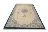 Corner of vintage Indian Peking rug with germinating plant motif, plush ivory pile, and blue border.