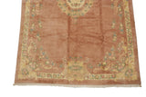 Floral border and pale gold design on a rose vintage Indian Aubusson carpet with fringe.
