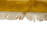 Thick saffron yellow wool pile with intact ivory selvage and fringe, showing a small stain.
