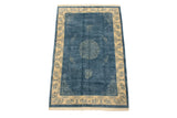 Corner of vintage Peking rug; denim blue field, ivory border, cloudband motifs and germinating plants.