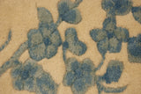 Detailed view of the plush wool pile with sky blue scrolling vinery on an ivory field.