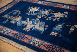 Bottom corner of a vintage Chinese Peking rug with terracotta border, geometric motifs, and white fringe.