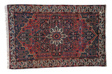 Vintage Persian Baktiari rug with concentric medallions and floral vines in brick red and navy blue.