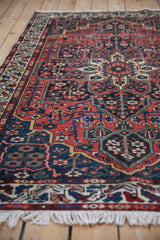Low angle perspective on a vintage Bakhtiari rug's brick red field and navy motifs.