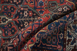 Draped view of a vintage Baktiari rug highlighting its brick red and navy floral pattern.