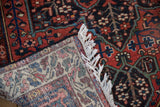 Folded corner of a vintage Baktiari rug showing its hand-knotted back and fringe.