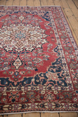 Low angle view of a vintage Baktiari rug's detailed medallion, navy spandrels, and rich cherry red field.