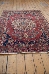Vintage Baktiari rug seen from an angle, highlighting the intricate central medallion and navy spandrels.