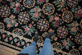 Dense black pile of a vintage Indian rug with repeating Arts and Crafts floral roundels in blush and celadon.