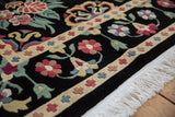 Corner of a vintage Indian carpet showing the dense, full pile, floral border, and intact ivory fringe.