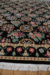 Close view of the dense pile, floral border, and clean ivory fringe on a vintage Indian rug.