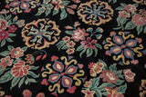 Detailed view of floral roundels and blossoming buds on the carpet's dense black pile.