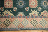 Green blossomed floral field of vintage Indian rug with geometric diamond border.