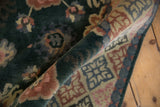 Rolled vintage Indian Arts and Crafts rug with blossomed floral motifs and geometric border.