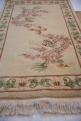 Embossed ivory Peking rug with pink dragon, cloudband motif, and green lotus border.