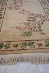 Thick, dimensional pile of a Peking rug, featuring pink dragon and cloudband motifs.