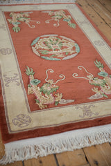 Pictorial dragon motif in celadon green and terra cotta, showing plush pile and fringe.