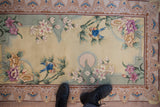Vintage Chinese pictorial rug: blue lovebirds on bamboo, embossed flowers, ivory field, shown with feet.