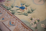 Embossed texture of lovebirds, bamboo, and intricate curvilinear border on a Chinese rug.