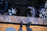 Blue floral blossom motif sprawling across charcoal pile and platinum border.