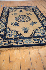 Vintage Peking rug's cobalt blue border, inner pearl detail, and ivory field vase.