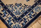 Corner of vintage Peking rug with cobalt blue vinery, pearl border, and fringe.
