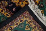 Ivory fringe, black selvage, and patterned emerald green border of the vintage Agra rug.