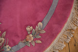 Close-up of the bubblegum pink Art Deco round rug's edge, original floral spray, and macrame fringe.