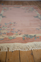 Close-up of embossed pastel floral sprays on dusty rose vintage Art Deco rug with ivory fringe.