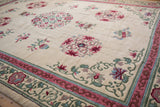 Vintage Japanese Peking rug corner showcasing pink floral planter vases and blue cloudband designs on ivory.
