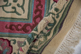 Plush pile in ivory, pink, green showing cloudband motifs and fringed edge.