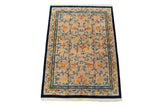 Corner of Indian Arts and Crafts carpet: beige field, blue vinery, golden buds, cobalt border, tinted fringe.