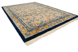 Indian Arts and Crafts rug corner with cobalt border, beige field, blue vinery, and tinted fringe.