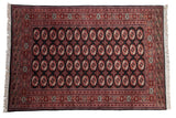 Vintage Bokhara carpet with repeating geometric gul medallions in red and ivory over a black field.