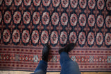 Detailed brick red gul medallions and border on a navy Bokhara rug with plush pile.