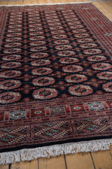 Vintage Bokhara carpet: brick red and ivory gul medallions on deep blue, geometric border.