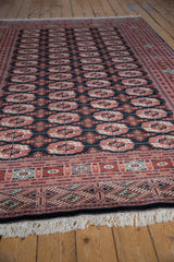 Crisp antique ivory fringe and geometric brick red, navy border of a fine Bokhara carpet.