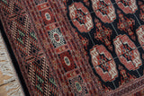 Vintage Bokhara rug's brick red geometric border, navy gul medallions, and soft ivory fringe.
