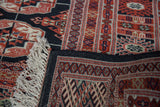 Vintage Bokhara rug folded, revealing red gul medallions, soft white fringe, and black selvage.