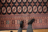 Plush wool pile showing the intricate border and black field with rust gul medallions.