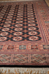 Low angle view of a vintage Bokhara carpet's plush, lustrous pile and detailed geometric border.