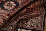 Corner detail of a fine Bokhara carpet with plush wool pile, black border, and clean ivory fringe.