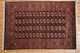 Finely knotted repeating gul medallions in rust and ivory on a plush vintage Bokhara carpet.